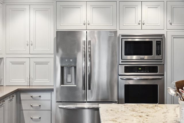 kitchen featuring light stone countertops, white cabinets, and stainless steel appliances