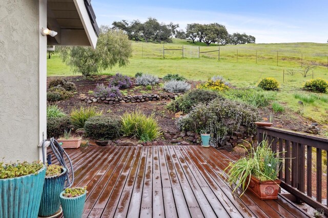 deck featuring fence, a rural view, and a yard