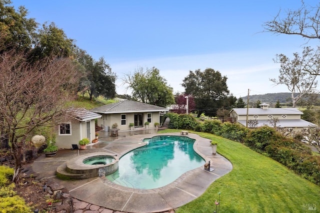 view of pool with a pool with connected hot tub, a patio area, a storage structure, an outbuilding, and a lawn
