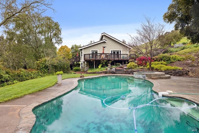 view of swimming pool featuring a lawn, a pool with connected hot tub, and a deck
