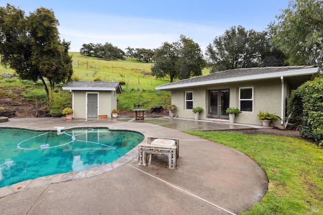 outdoor pool with an outdoor structure, french doors, a yard, and a patio area