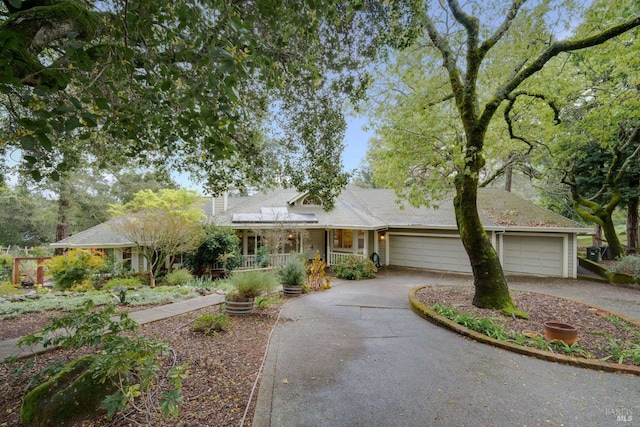single story home with a porch, driveway, and a garage