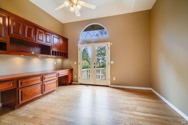 unfurnished office featuring french doors, built in study area, light wood finished floors, baseboards, and ceiling fan