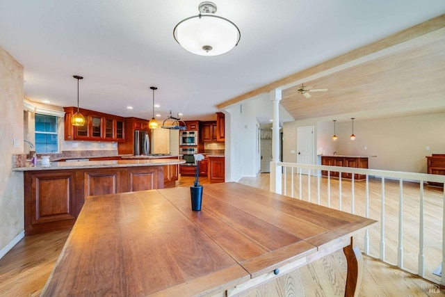 dining space featuring ornate columns, a ceiling fan, baseboards, and light wood-type flooring