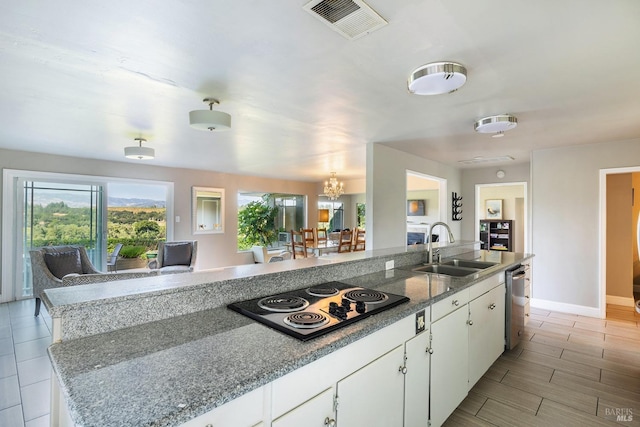 kitchen featuring visible vents, stainless steel dishwasher, black electric cooktop, a sink, and white cabinets
