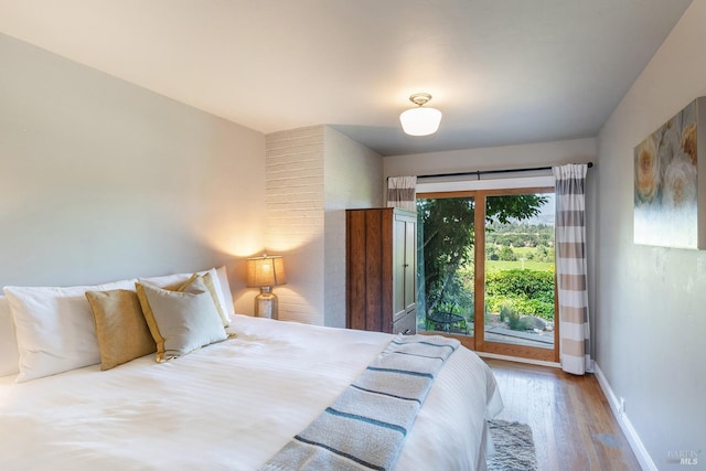 bedroom featuring access to outside, baseboards, and wood finished floors