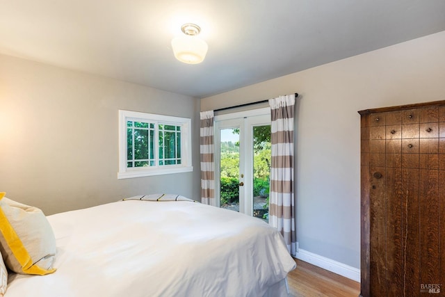 bedroom featuring access to outside, baseboards, and wood finished floors