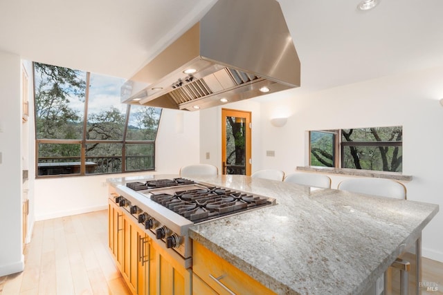 kitchen with light stone counters, ventilation hood, baseboards, and stainless steel gas cooktop