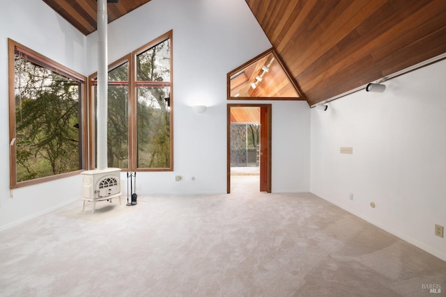 interior space featuring wood ceiling, lofted ceiling, a wood stove, and carpet
