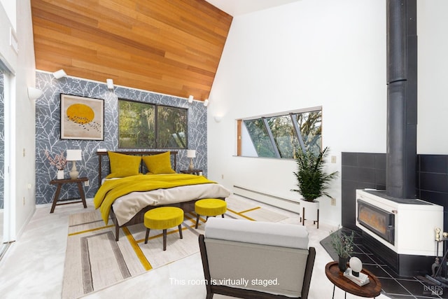 bedroom with baseboard heating, high vaulted ceiling, an accent wall, a wood stove, and wooden ceiling