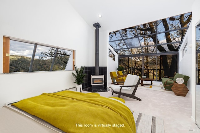 carpeted bedroom featuring high vaulted ceiling and a wood stove