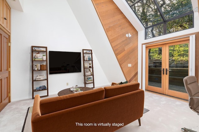 living area with french doors, a towering ceiling, and light colored carpet