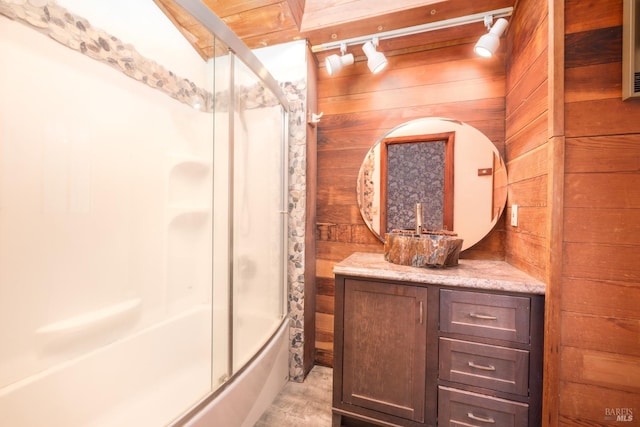 bathroom with wood walls, vanity, and shower / bath combination with glass door