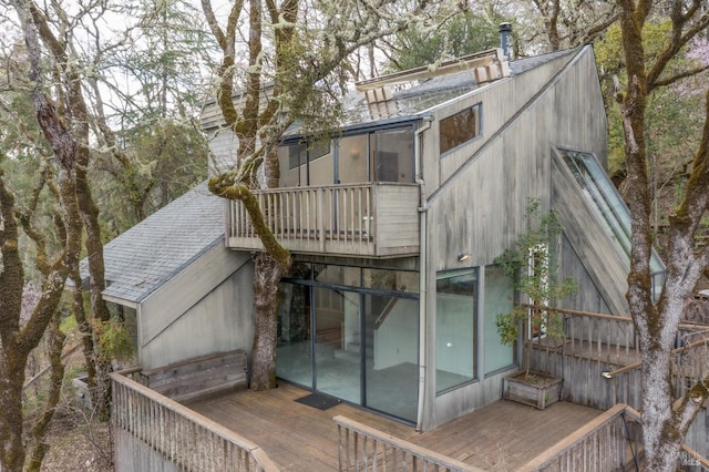 rear view of house featuring a wooden deck and a sunroom