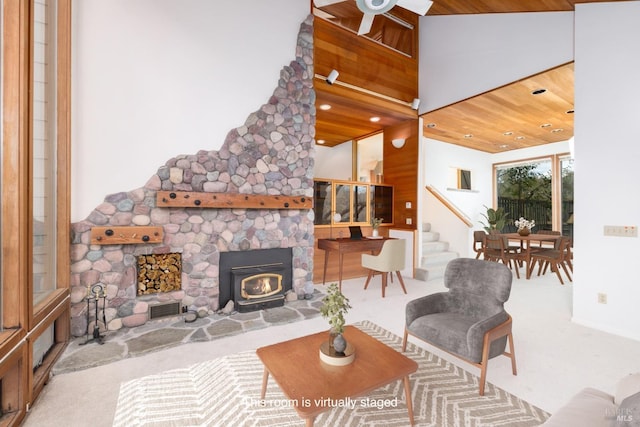 carpeted living area featuring stairway, a wood stove, a ceiling fan, and visible vents