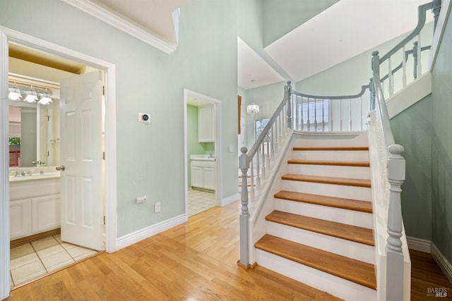 stairway featuring baseboards, ornamental molding, and wood finished floors