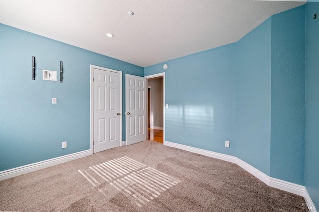 unfurnished bedroom featuring carpet floors, baseboards, and a closet