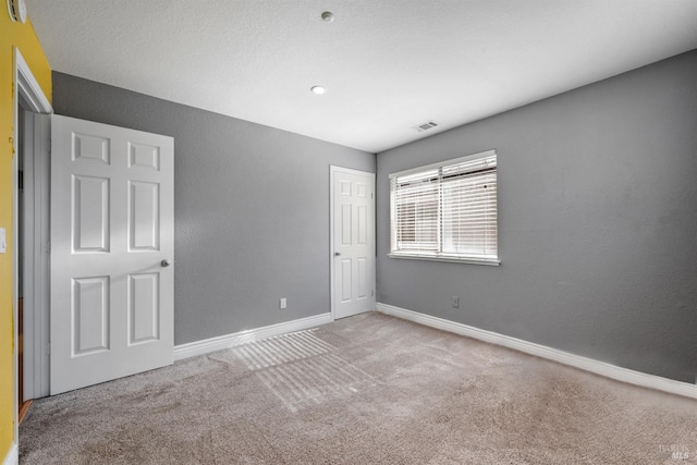 unfurnished bedroom featuring baseboards, carpet flooring, and visible vents
