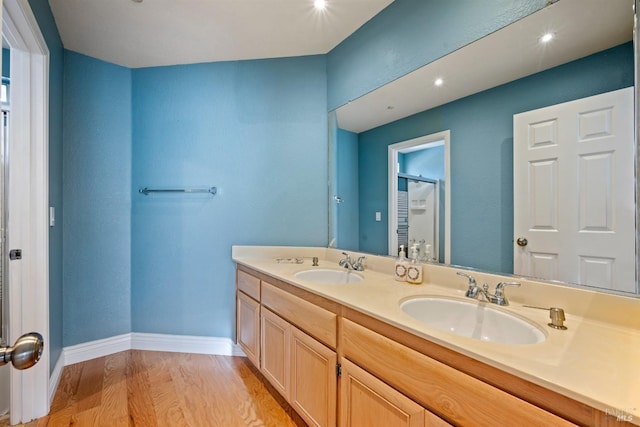 full bathroom with a shower, a sink, wood finished floors, and double vanity
