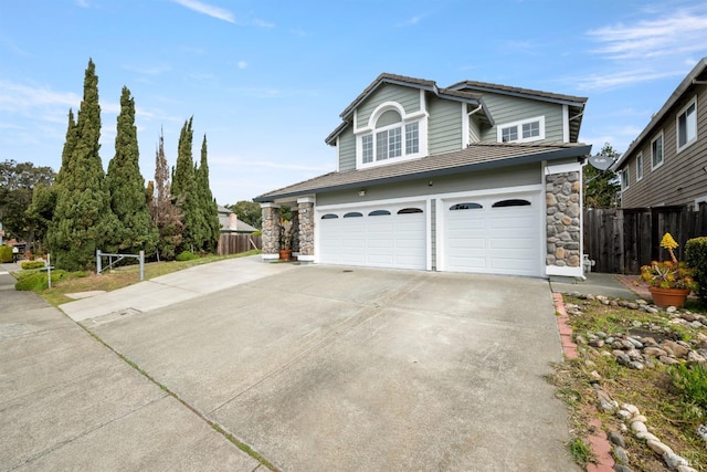view of front of house with a garage, fence, stone siding, and concrete driveway