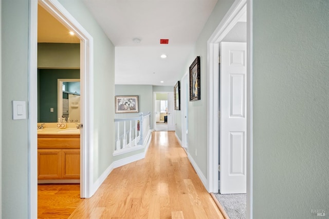 hallway featuring light wood-style floors, baseboards, and recessed lighting