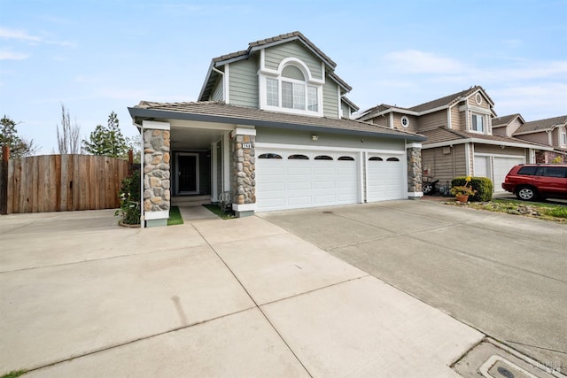 view of front of house with fence, a tile roof, stone siding, a garage, and driveway