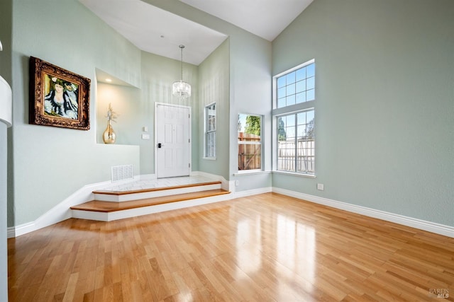entryway with visible vents, wood finished floors, high vaulted ceiling, and an inviting chandelier