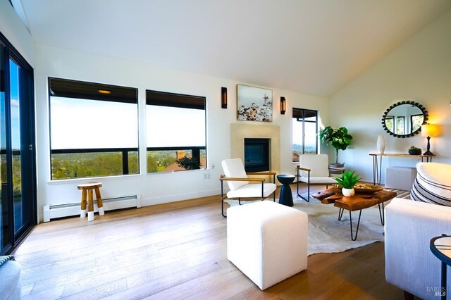 living area featuring a towering ceiling, baseboards, and light wood-style floors