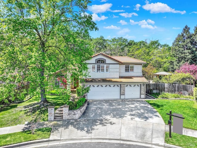 view of front of house with concrete driveway, fence, an attached garage, a tiled roof, and a front yard