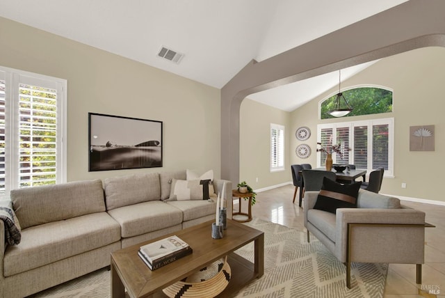 living area with light tile patterned flooring, high vaulted ceiling, baseboards, and visible vents