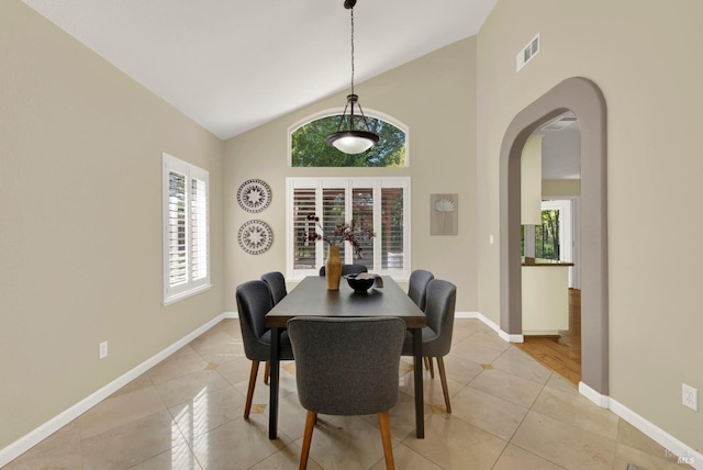 dining room featuring light tile patterned flooring, high vaulted ceiling, visible vents, baseboards, and arched walkways