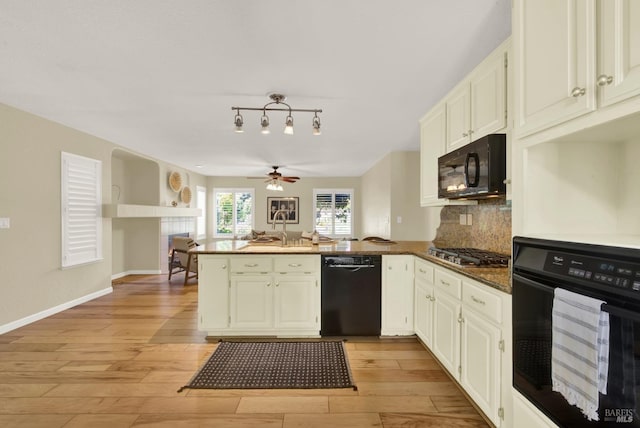kitchen with tasteful backsplash, a sink, light wood-style flooring, a peninsula, and black appliances
