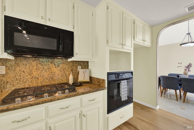 kitchen featuring tasteful backsplash, light wood-type flooring, visible vents, white cabinets, and black appliances