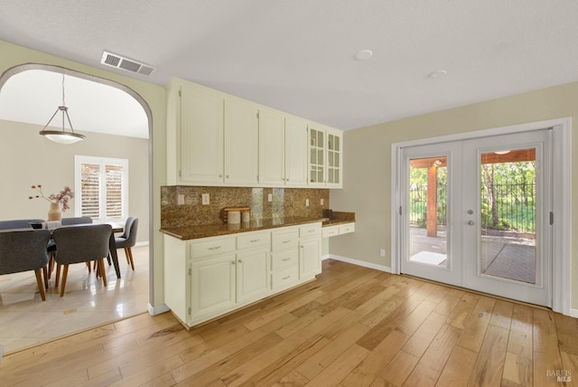 kitchen with tasteful backsplash, french doors, arched walkways, visible vents, and light wood-style flooring