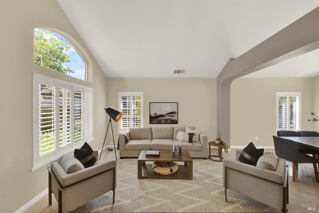 living area featuring high vaulted ceiling, baseboards, and visible vents