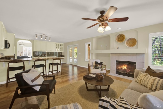 living area with baseboards, a fireplace, wood finished floors, and ceiling fan