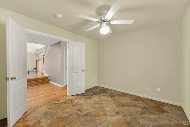 unfurnished room with stone finish floor, baseboards, and ceiling fan
