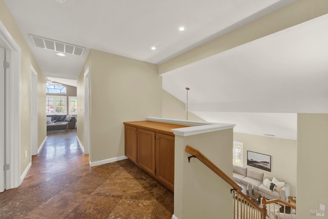 hall featuring an upstairs landing, lofted ceiling, baseboards, visible vents, and recessed lighting