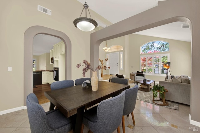 dining area with arched walkways, baseboards, visible vents, and light tile patterned flooring