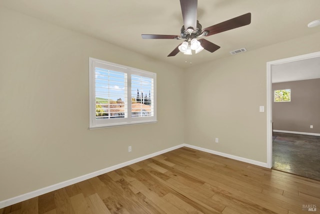 unfurnished room featuring a ceiling fan, visible vents, baseboards, and wood finished floors
