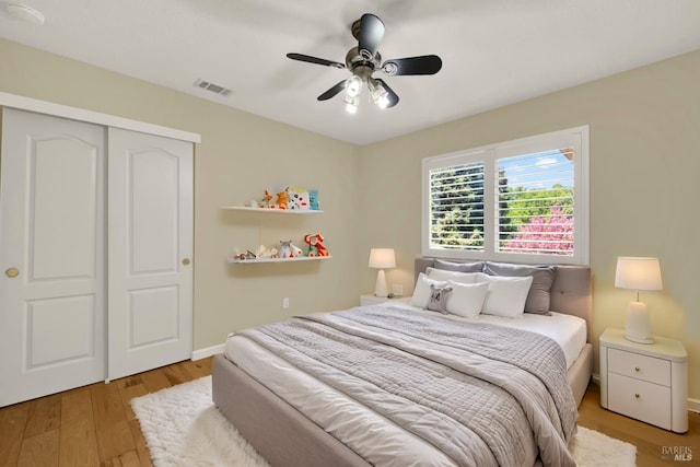 bedroom with baseboards, ceiling fan, visible vents, a closet, and wood finished floors