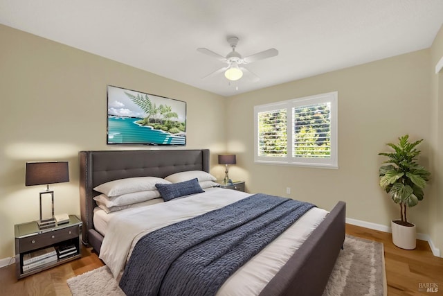 bedroom featuring baseboards, wood finished floors, and a ceiling fan