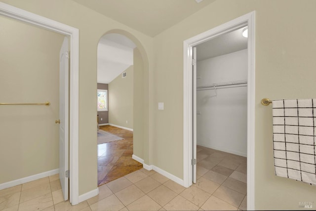 interior space featuring baseboards, visible vents, arched walkways, and light tile patterned floors