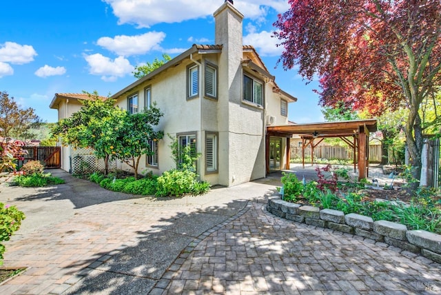rear view of house with a fenced backyard, a chimney, stucco siding, and a patio