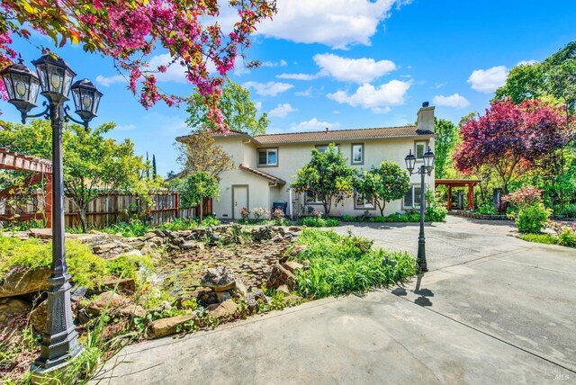 view of front of house featuring stucco siding, fence, and a chimney
