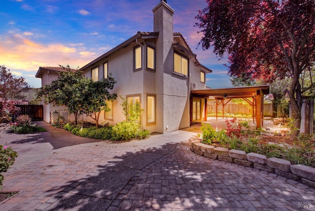 view of front of property with a fenced backyard, a chimney, stucco siding, and a patio