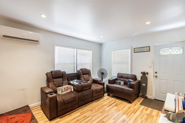 living room with an AC wall unit, baseboards, light wood finished floors, and recessed lighting