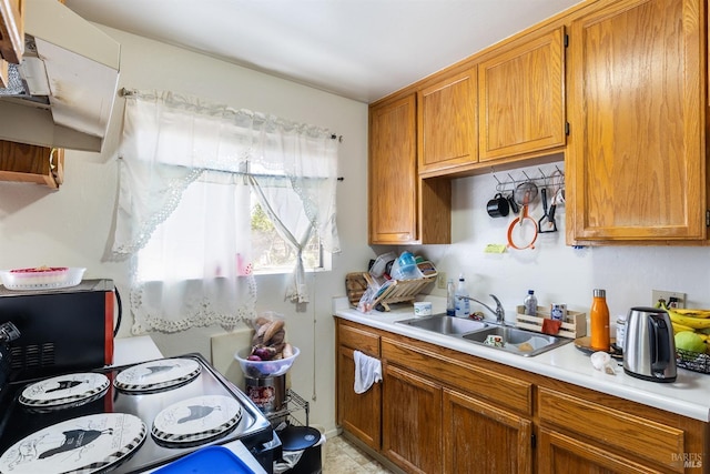 kitchen with light countertops, a sink, and brown cabinetry