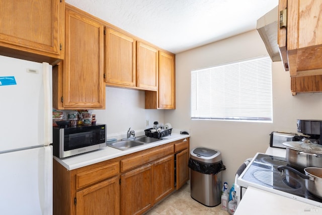 kitchen with light countertops, a sink, and freestanding refrigerator