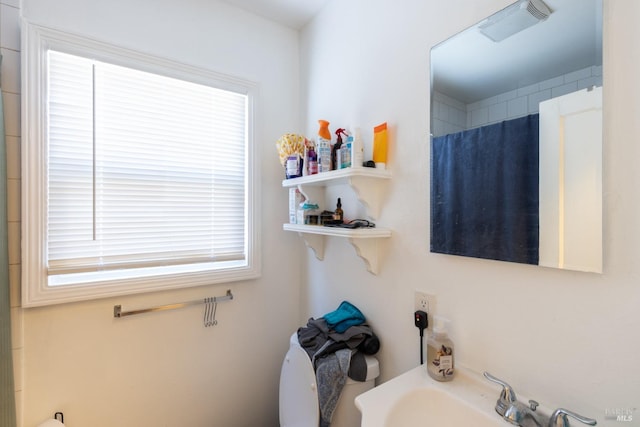 bathroom with a sink, curtained shower, and visible vents